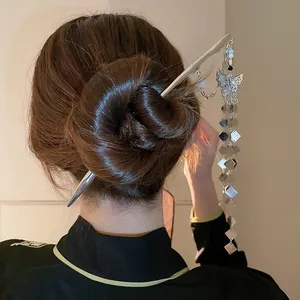 Elegant butterfly hair stick with long silver tassels shown in a stylish hair bun