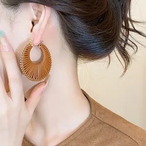Close-up detail of a stylish brown woven hollow hoop earring worn by an Asian model