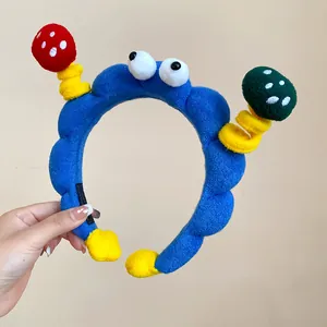 Detailed view of a funny blue plush headband featuring googly eyes and cute 3D mushrooms.