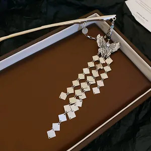 Close-up of silver butterfly hair pin with cascading diamond-shaped tassels on brown box