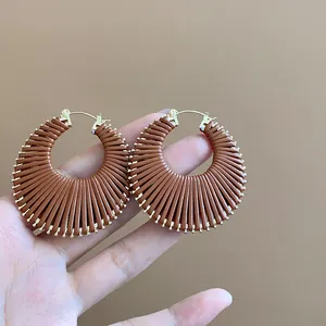 Handheld detail view of brown pleated fan-shaped circular hoop earrings with gold