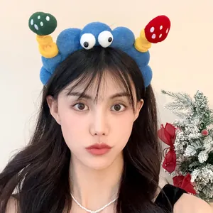 Quirky blue plush headband with cartoon eyes and mushrooms worn by an Asian woman