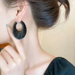 Macro view showing the pleated texture of the black woven fashion hoop earring