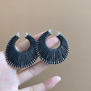 Close-up of black woven hoop earrings showing intricate radial thread texture