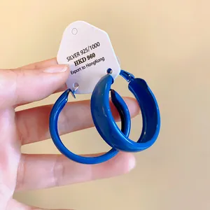 Close-up of minimalist Klein blue spray-painted hoop earrings with silver needles