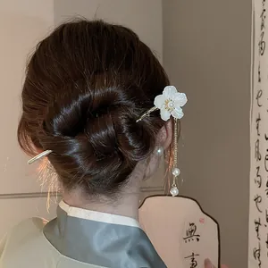 Elegant white flower hair stick with pearl tassels worn in a traditional bun hairstyle
