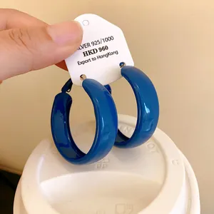 Macro view of Klein blue minimalist spray-painted hoop earrings shown on a white tag