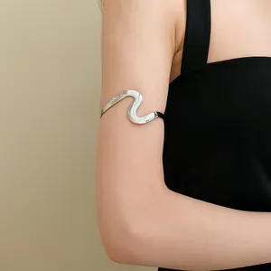 Minimalist silver wave arm cuff bracelet with twisted metal design on model's upper arm