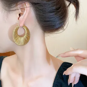 Close-up shot of a stylish golden textured hoop earring worn by a model on her ear