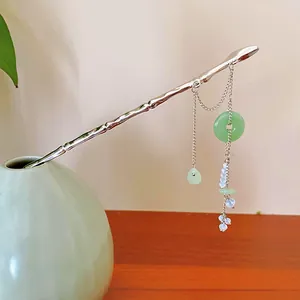 Close-up of elegant silver bamboo-style hair stick with green jade donut tassel detail