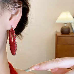 Red textured hoop earrings with silver bead trim on a model