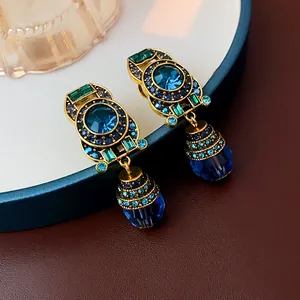 Vintage-style gold-tone drop earrings featuring blue resin and crystals.