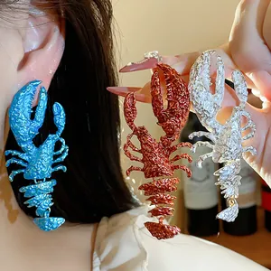 Detailed macro view showing the textured finish of blue, red, and silver lobster earrings.