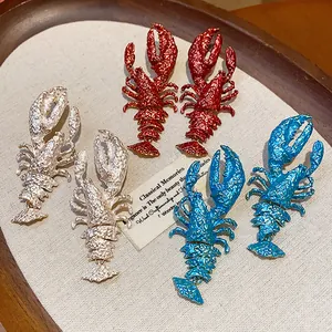 Close-up of oversized painted lobster earrings in red blue and silver metallic finishes