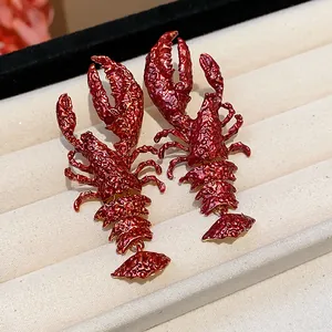 Close-up view of vibrant red textured lacquer lobster earrings displayed in a jewelry tray.