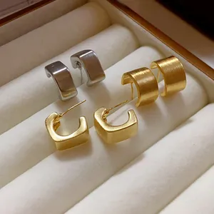 Primer plano de los pendientes geométricos de metal cepillado en tonos oro y plata