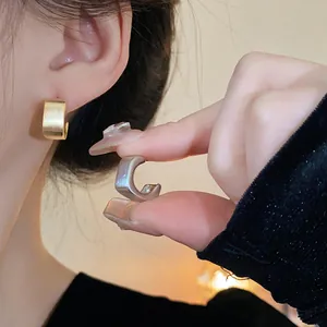 Detalle de pendientes geométricos cuadrados de metal cepillado con aguja de plata, oro
