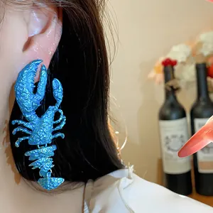 Close-up detail of exaggerated blue painted lobster earrings worn on a model's ear