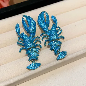 Macro view of vibrant blue lobster statement earrings with a unique textured paint finish.