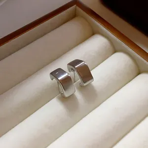 Primer plano de pendientes geométricos cuadrados minimalistas con acabado en plata cepillada.