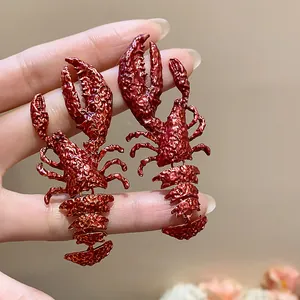Detail close-up showing crinkled red metallic texture of unique lobster-shaped earrings.