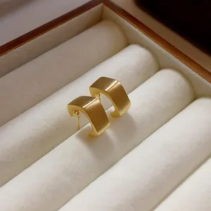 Detalle de primer plano de la elegante textura mate cepillada de los pendientes cuadrados.