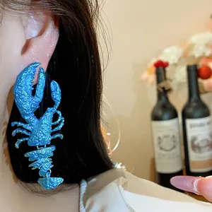 Close-up detail of vibrant blue spray-painted lobster earring with textured finish