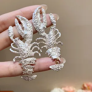 Macro view of textured cream-painted lobster earrings showing intricate anatomical details