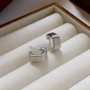 Vista macro detallada de pendientes cuadrados de plata cepillada en caja de joyas