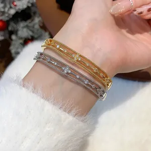 Detailansicht luxuriöser vergoldeter Armreifen mit Zirkon-Hulu-Design am Handgelenk.