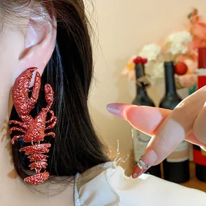 Close-up detail of a large textured metallic red spray-painted lobster drop earring