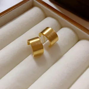 Primer plano de pendientes cuadrados dorados con elegante textura de metal cepillado