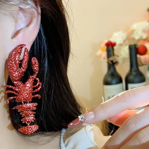 Close-up of a unique large red spray-painted lobster earring worn on a model's ear