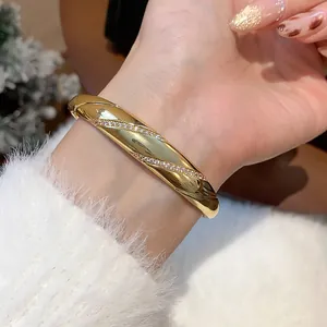 Detailansicht eines vergoldeten Zirkonia-Armreifs am Handgelenk mit feiner Textur.