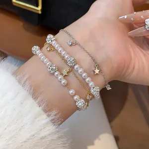 Detailed view of elegant pearl and zircon star charm bracelets layered on a wrist