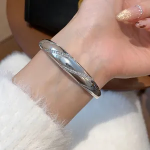 Detailansicht eines eleganten silbernen Armreifs mit funkelnden Zirkonia Steinen am Handgelenk