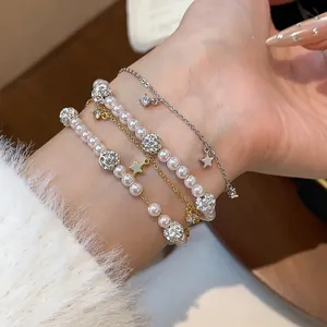 Close-up showing a layered set of elegant pearl bead and zircon star bracelets on wrist.
