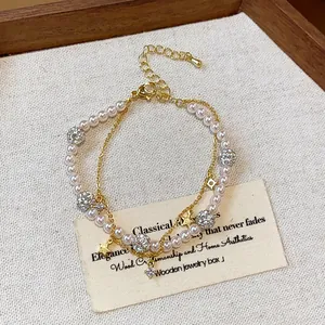 Detail of a double-layer pearl bracelet with zircon balls and gold star charms