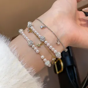Close-up view of a layered bracelet with pearls, star charms, and zircons on a wrist