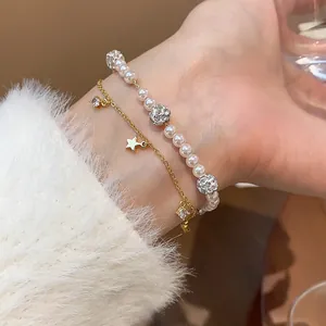 Detail of double-layer bracelet with pearls, crystal balls, and a gold star charm on wrist.