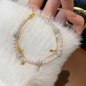 Detailed close-up of a double-layer bracelet with pearls, pavé zircon balls, and star charms.