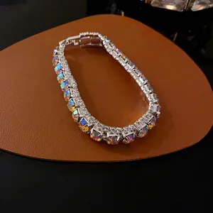 Close-up of sparkling iridescent rhinestones on a silver-toned geometric buckle bracelet.