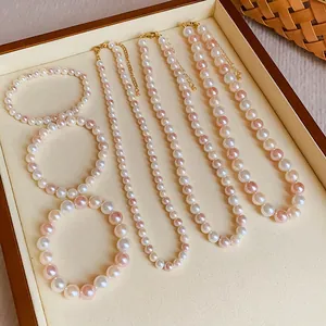 Close-up detail of white and pink pearl bracelets and necklaces in a wooden tray