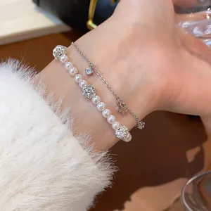 Detailed view of an elegant double-layered pearl and zircon star bracelet on a wrist.