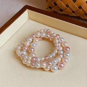 Detail view showing the elegant triple-strand elastic pearl bracelet in pink and white
