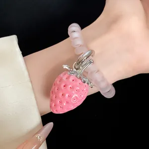 Detailed macro view of a pink resin strawberry pendant on a soft frosted spiral bracelet