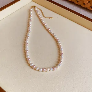 Close-up of elegant pearl necklace with white and pink pearls on cream jewelry tray