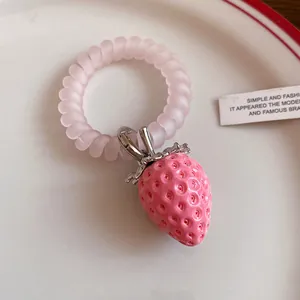 Macro detail of a sweet pink resin strawberry pendant attached to a spiral telephone wire band