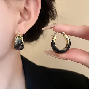 Detail shot of vintage gold U-shaped hoop earrings with dark marbled resin accent