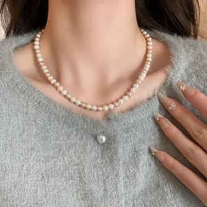 Detailed view of a multi-color pearl necklace worn on a neck over a grey sweater